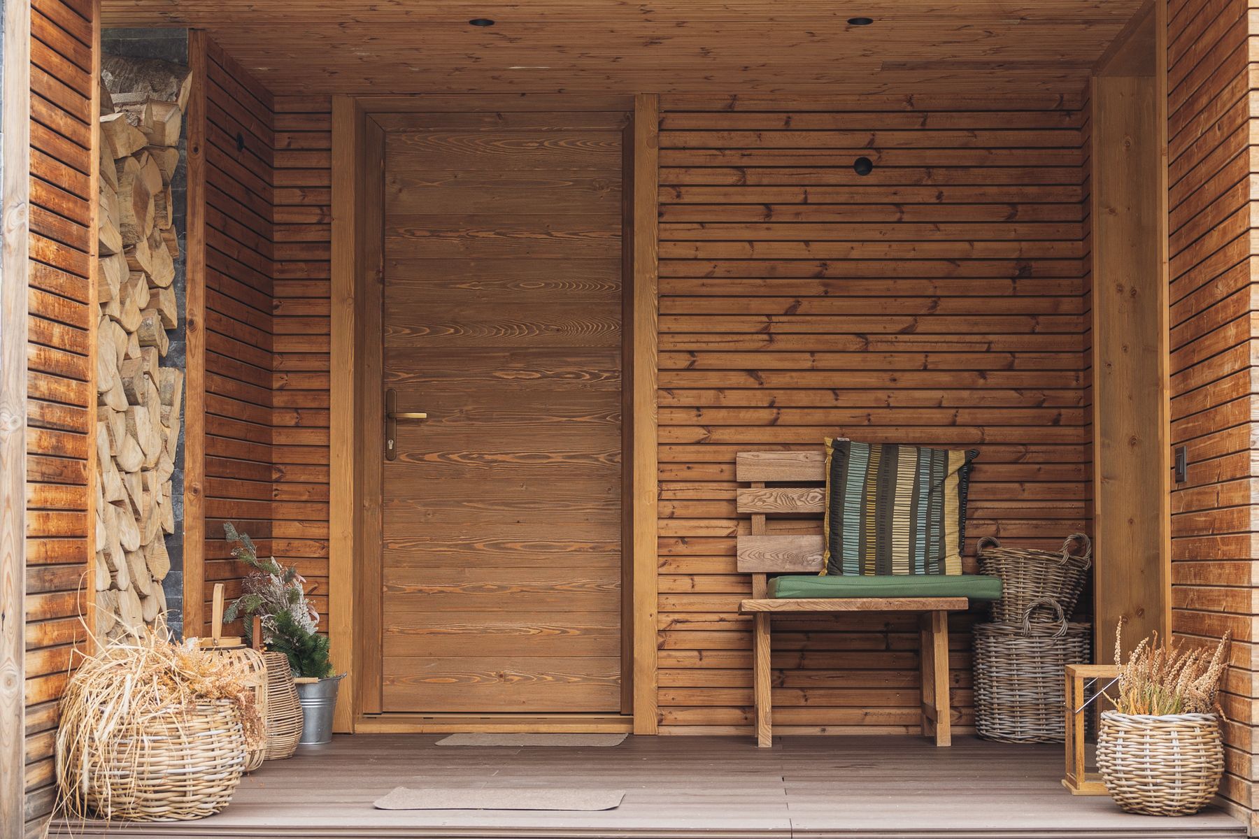 A welcoming rustic porch with a wooden bench, baskets, plants, and secondhand finds